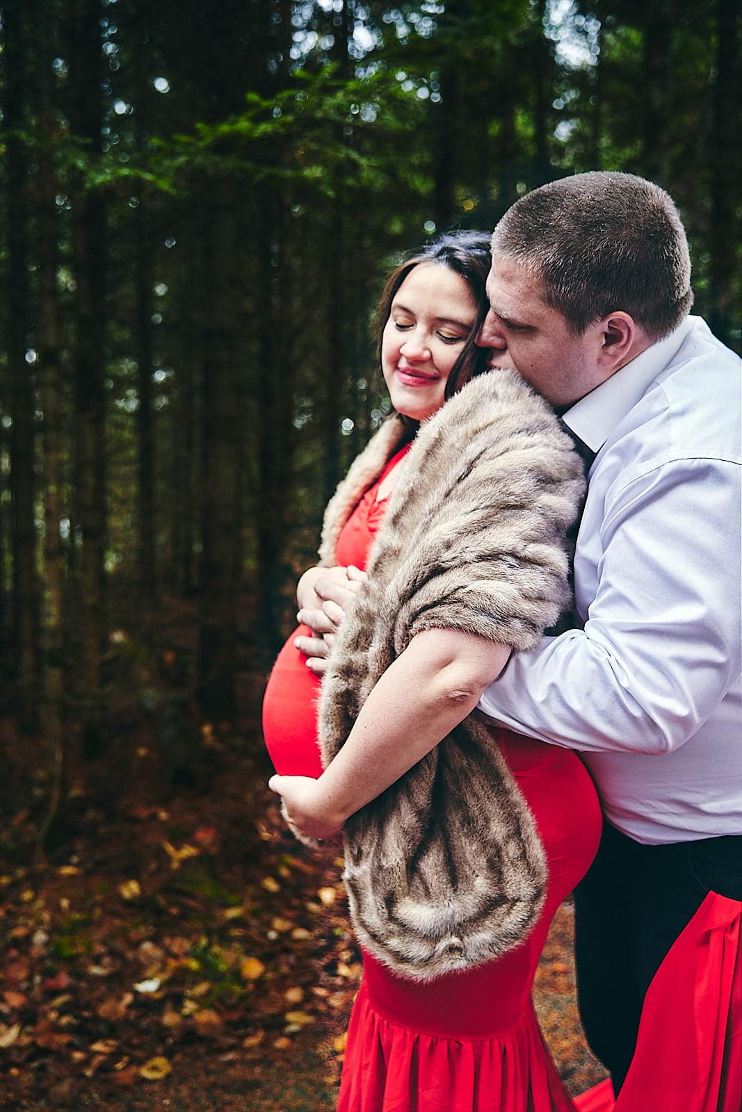 Femme enceinte et partenaire en séance photo en forêt.