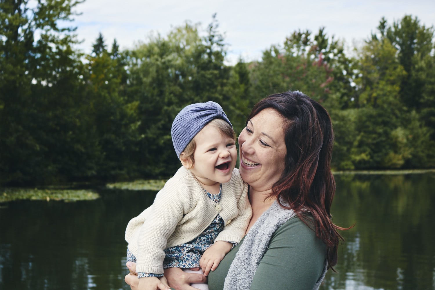 Mère et enfant souriants près de l'étang en plein air.