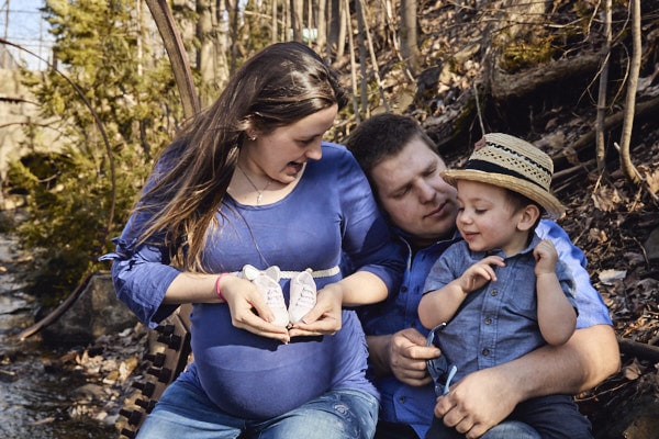 Famille heureuse en plein air, séance photo en forêt avec un bébé et un jeune garçon.