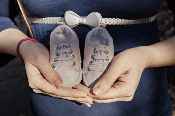 Chaussures de bébé dans les mains d'une femme enceinte.